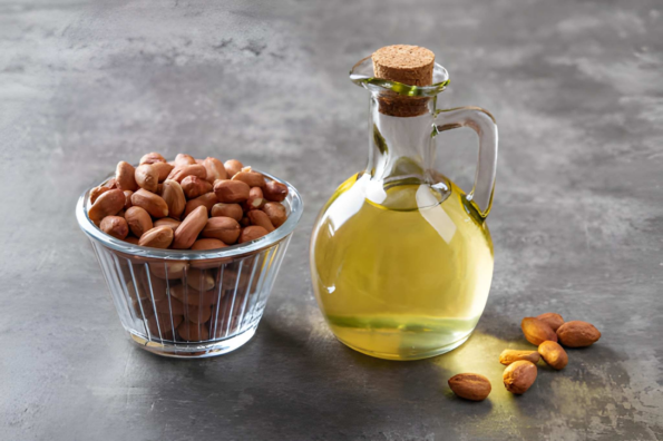 Peanut oil in glass bottle with raw peanuts.